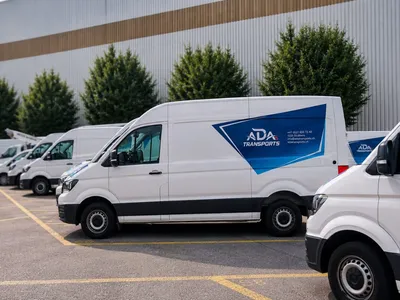 Flotte de VW Crafter blancs ADA Transports vus de profil sur le parking du dépôt