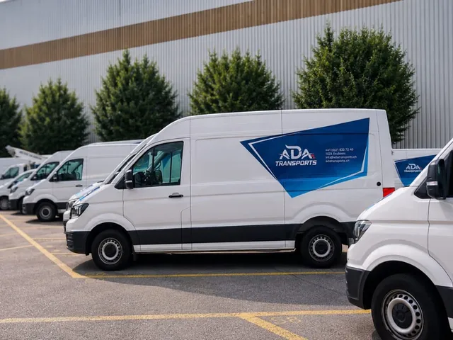 Flotte de VW Crafter blancs ADA Transports garée devant le dépôt d'Ecublens au coucher du soleil