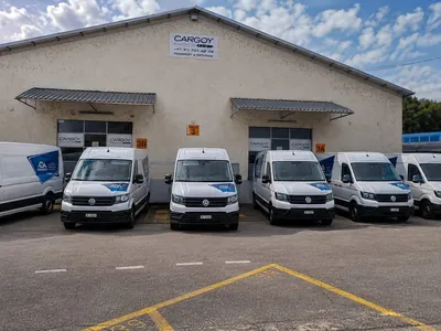 Flotte de VW Crafter blancs ADA Transports alignés de face devant le dépôt d'Ecublens